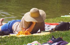 Une personne lisant, allongée dans l'herbe au soleil